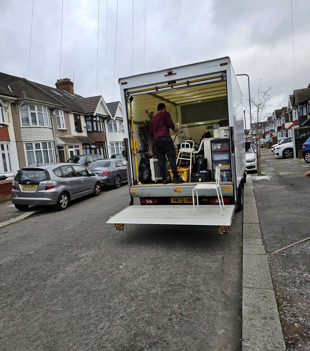 Van loaded with furniture and boxes outside a terraced house, tail-lift down